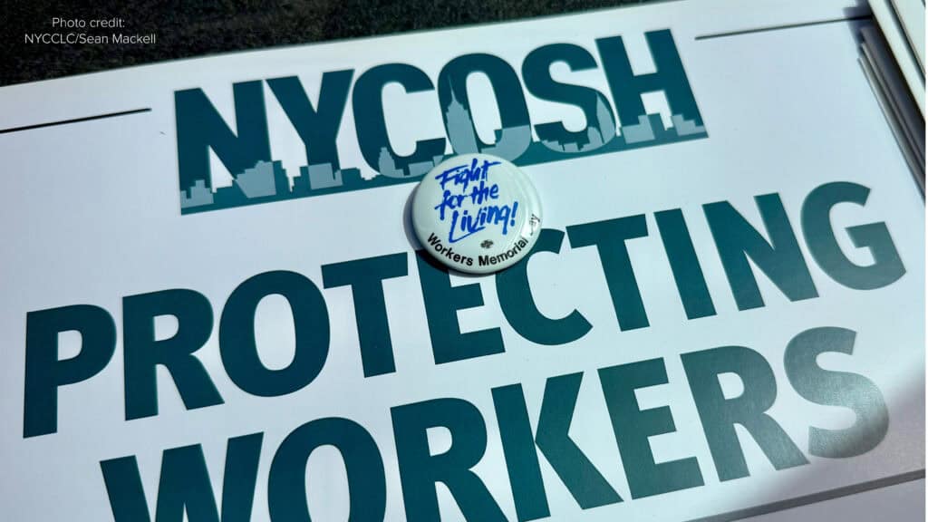 NYCOSH - A sign reads "NYCOSH Protecting Workers" with a button on top that says "Fight for the Living, Workers Memorial Day." Explore NYCOSH Resources and Reports. Photo credit: NYCCLC/Sean Mackell.